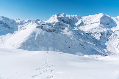 Group of people skiing in fresh powder snow in vast alpine landscape, gastein, austria.