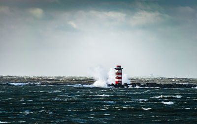 Lighthouse by sea against sky