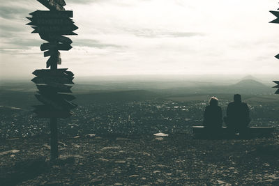 Rear view of people on landscape against sky