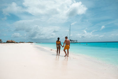 Rear view of women on beach against sky