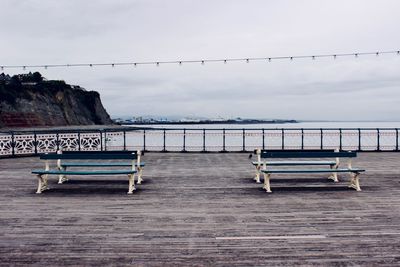 Empty bench by sea against sky