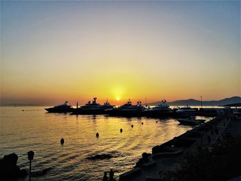 Silhouette boats in sea against clear sky during sunset