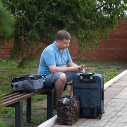 A man with bags and a suitcase calls a taxi to the station foreign city.