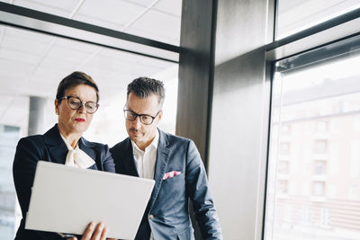 Senior businesswoman discussing with colleague over laptop in conference room at office