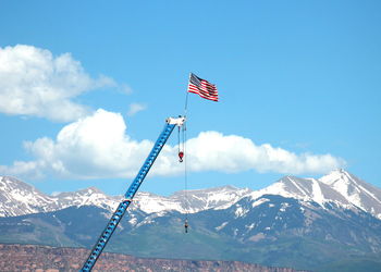 American flag waving on crane against snowcapped mountains