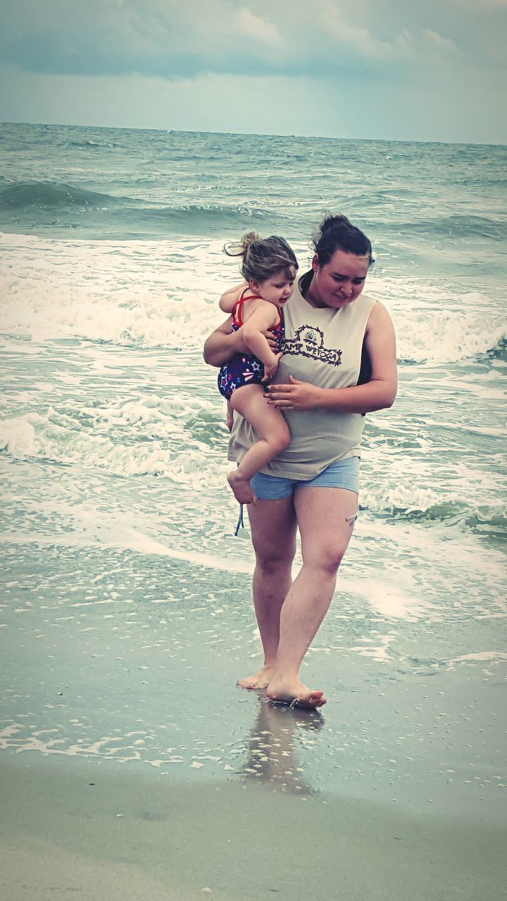 sea, water, lifestyles, leisure activity, beach, full length, person, young adult, shore, vacations, horizon over water, enjoyment, childhood, sunglasses, casual clothing, sand, happiness, young women