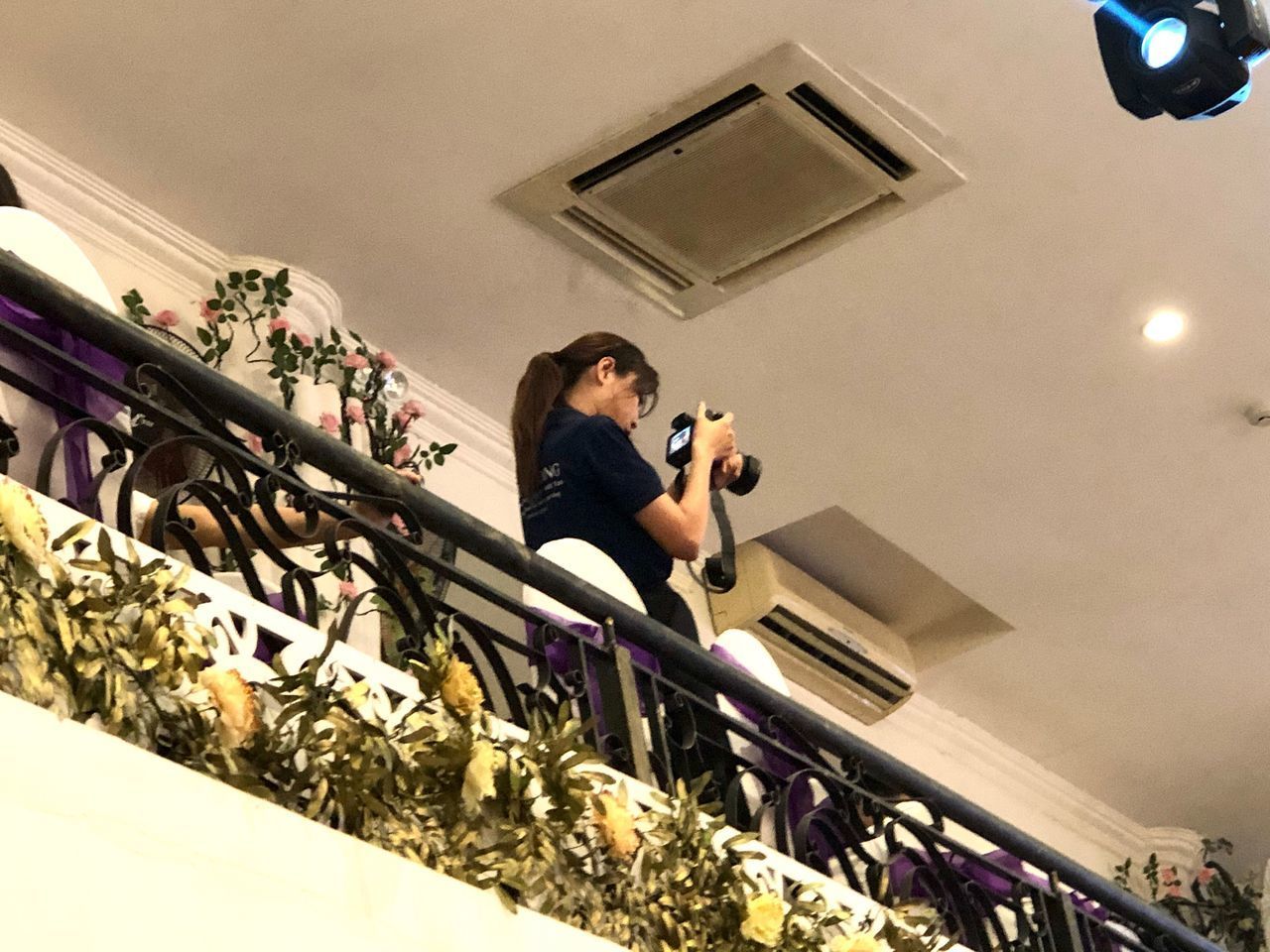 LOW ANGLE VIEW OF WOMAN PHOTOGRAPHING ON ILLUMINATED CEILING AT HOME