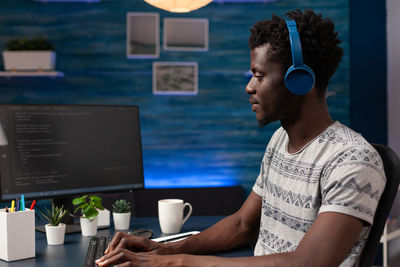 Side view of young man using laptop at office