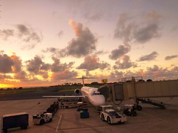 Airplane on runway against sky during sunset