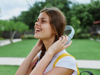 Side view of young woman looking away against trees