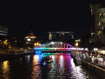 Illuminated bridge over river at night