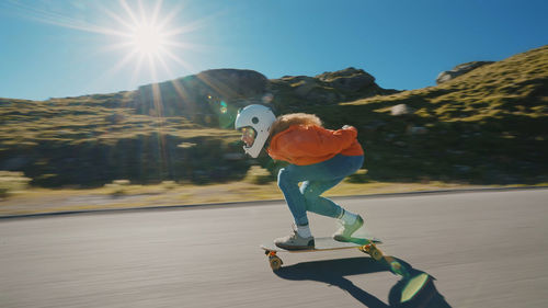 Rear view of man skateboarding on road