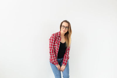 Portrait of young woman standing against white background