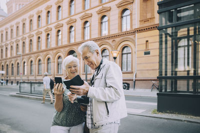Rear view of man holding woman walking in city