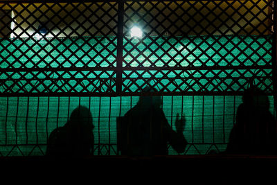 Shadow of people having discussion against fence