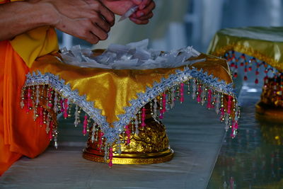 Midsection of monk standing by container with bags at temple