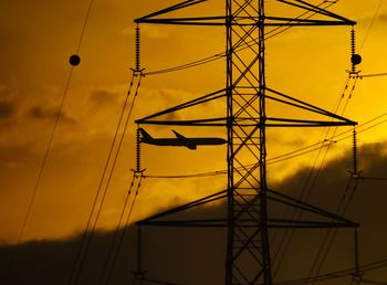 Silhouette. electric tower with airplane cross the sky