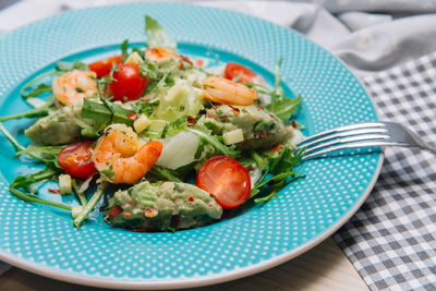 Shrimps salad with guacamole sauce, arugula, spices and chopped cherry tomatoes