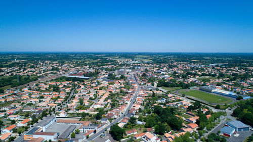 High angle view of town by sea against clear blue sky