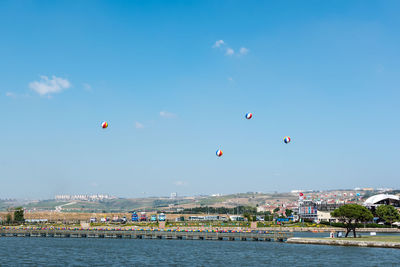 Hot air balloons flying over sea against blue sky