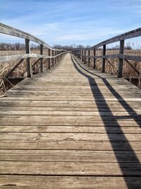 Footbridge leading towards bridge against sky