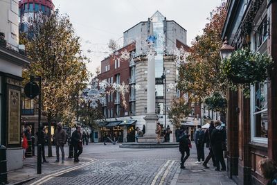 People walking on street amidst buildings in city