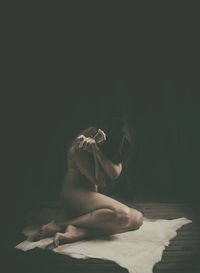 Woman kneeling on the floor on a goat rug ii