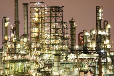 Illuminated factory against sky at night