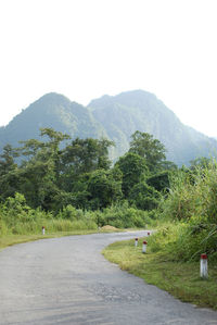 Empty road by mountains against clear sky