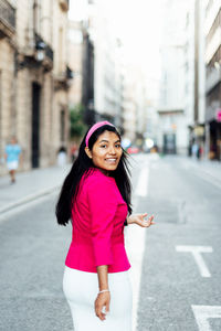 Portrait of smiling young woman standing on road in city