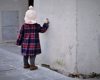 Rear view of woman standing against wall