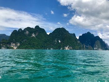 Scenic view of sea by mountains against sky