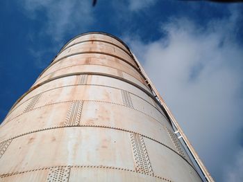 Low angle view of storage tank against cloudy sky