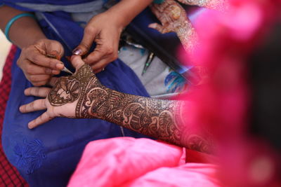 Close-up of woman applying henna tattoo on hand