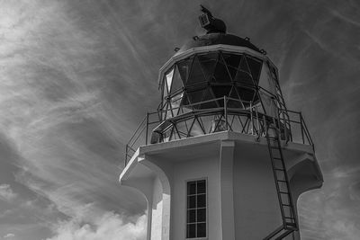 Low angle monochrome close-up view of lighthouse against sky with wispy clouds
