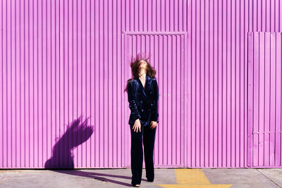 Full length of woman standing against pink wall