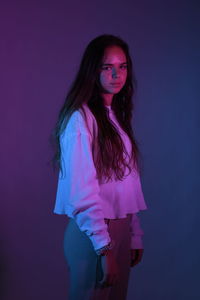 Portrait of teenage girl standing over purple background