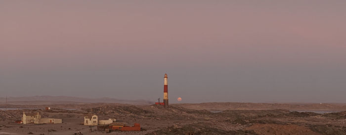 Lighthouse amidst buildings against sky