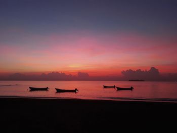 Silhouette boats in sea against sky during sunset