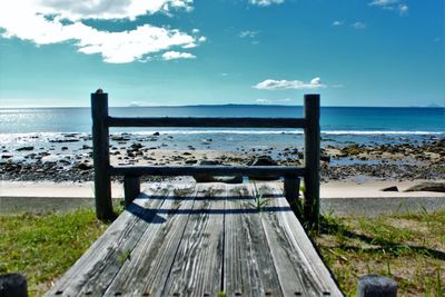 Wooden posts on beach against sky