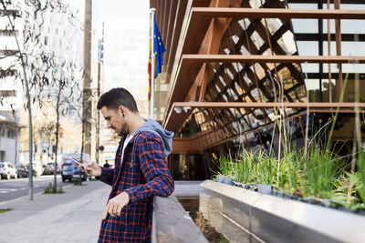 Side view of man using phone on street