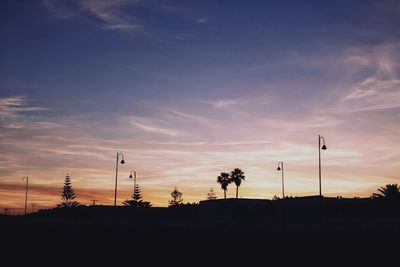 Silhouette of electricity pylon against sky during sunset