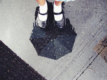 Low section of girls with umbrella reflection of wet footpath in rainy season