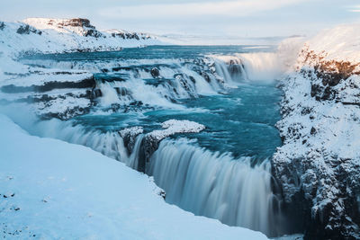 Scenic view of waterfall against sky during winter