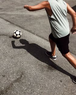 Low section of man playing soccer on street