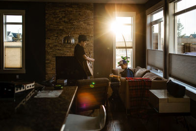 Brothers playing guitar at home with sun coming in window