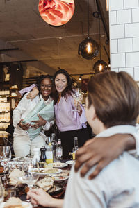 Happy female and male friends celebrating during party at bar