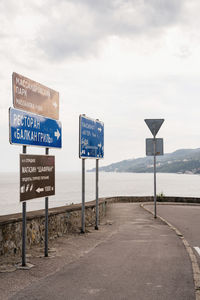 Information sign by road against sky