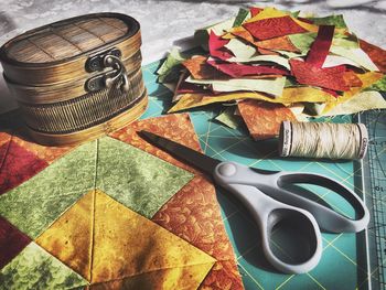 High angle view of fabric with container and scissor on table