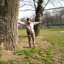 Full length of young man standing on tree trunk